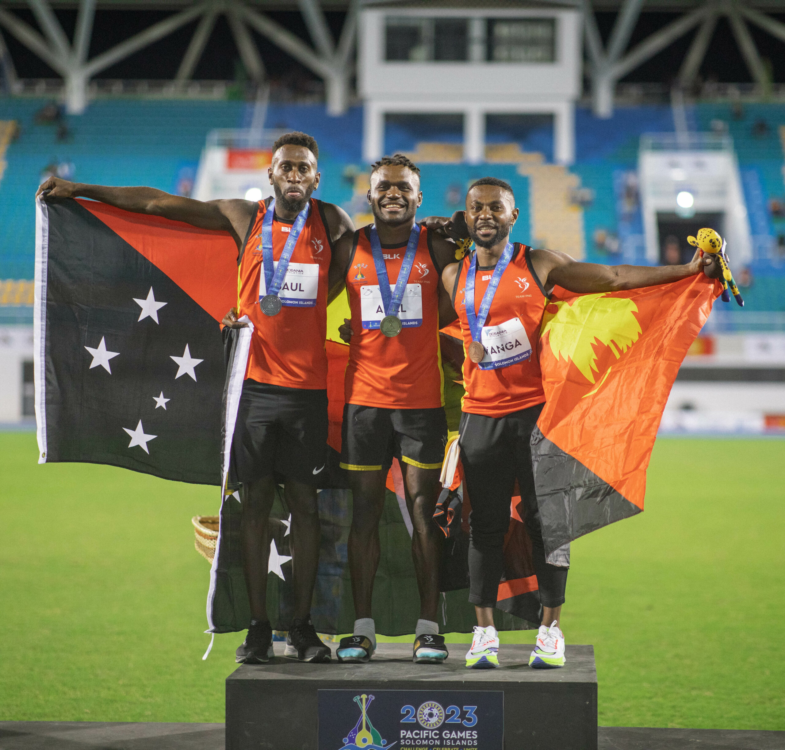 Three athletes from Papua New Guinea on a podim