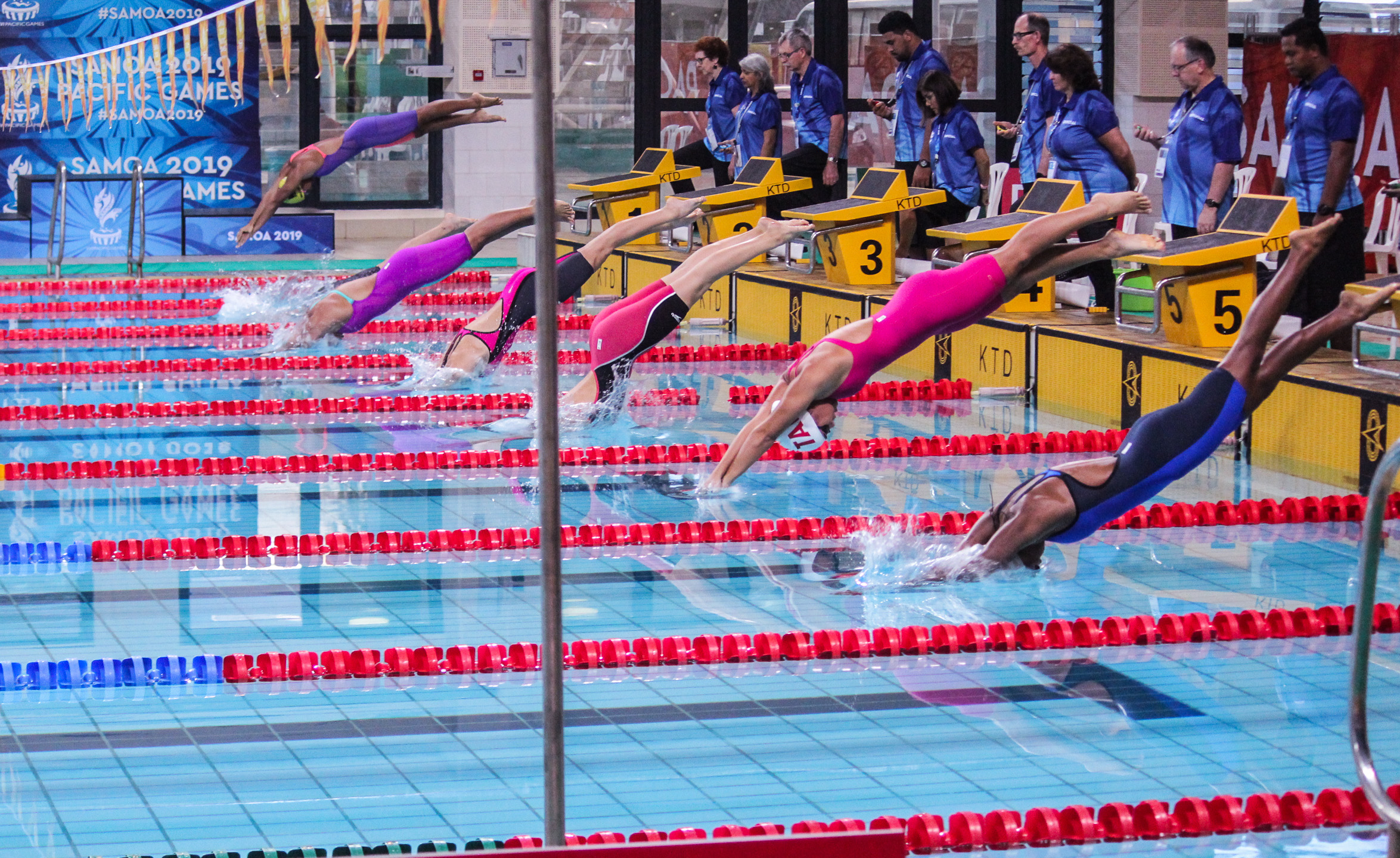 Swimmers jumping into a pool to race
