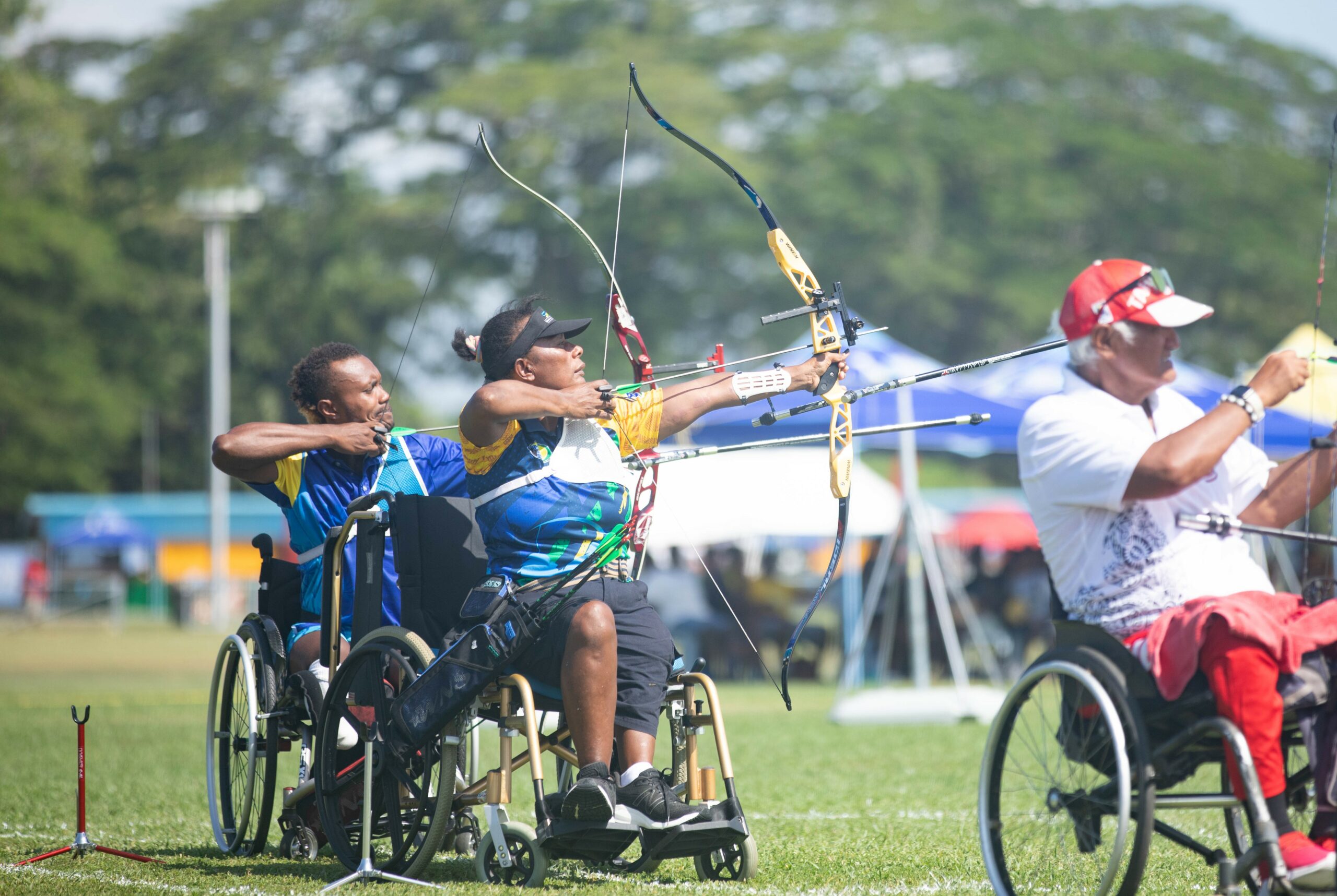People in wheelchairs competing in archery