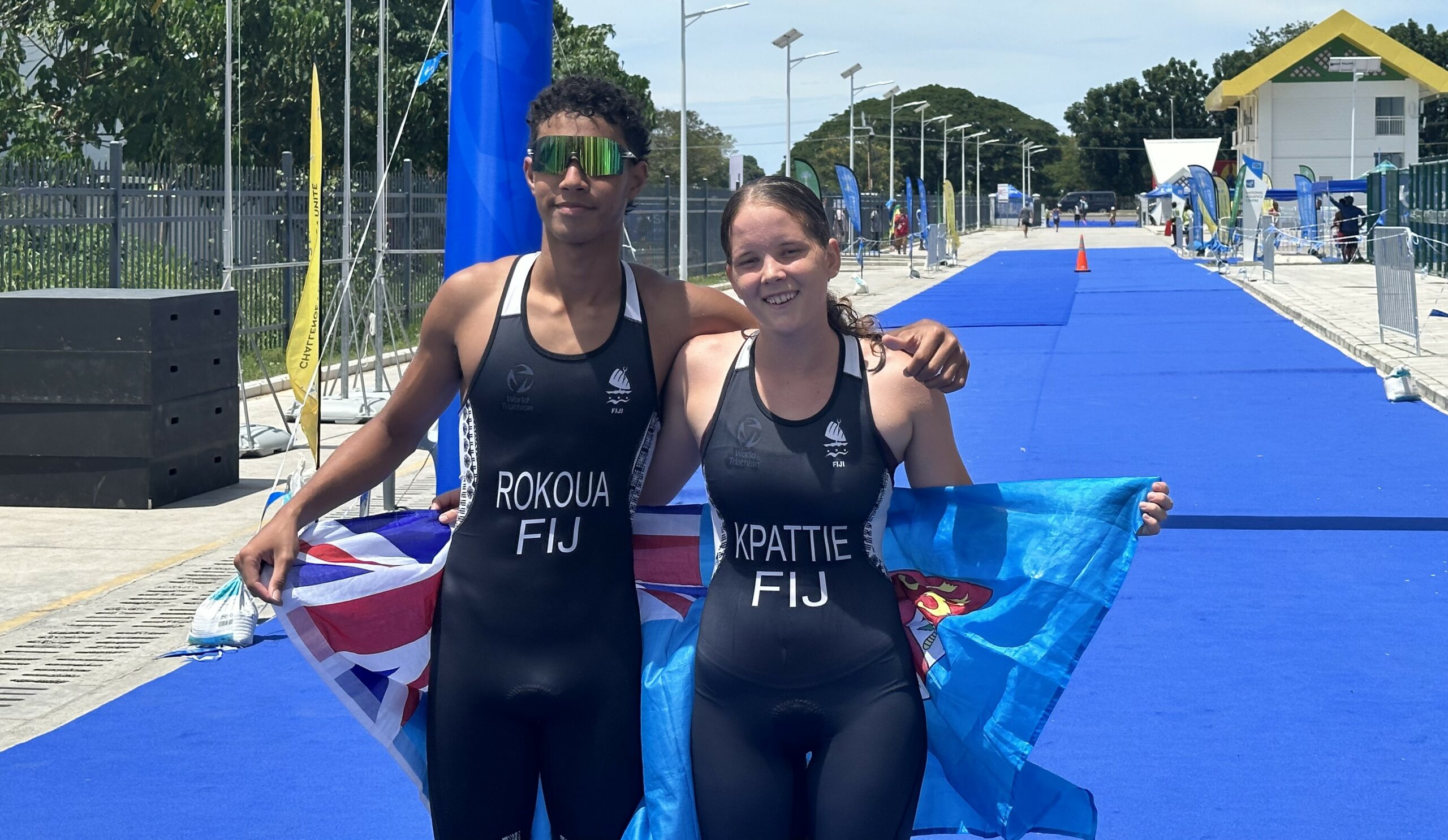 Two triathlon athletes holding a Fijian flag